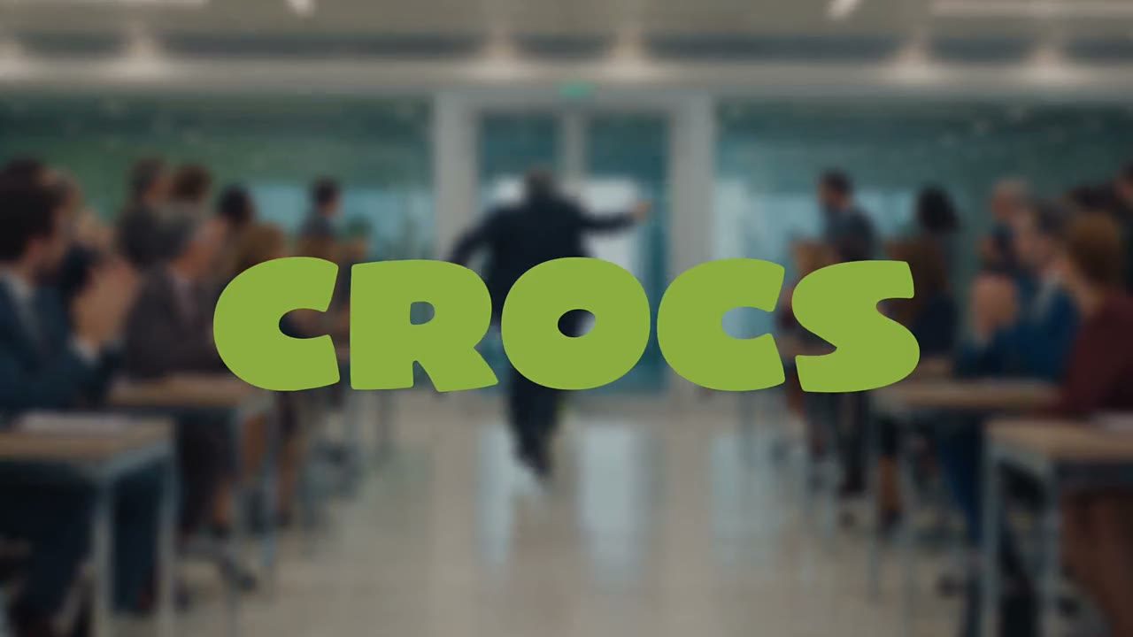 Fotogramma dello spot: scritta Crocs verde su un ufficio pieno di colleghi che applaudono